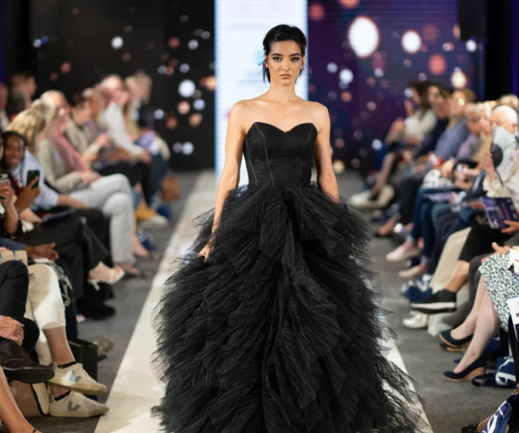 Model wears a dramatic black strapless tulle gown on the runway at Central London Alliance's London Fashion Week showcase, with seated audience watching