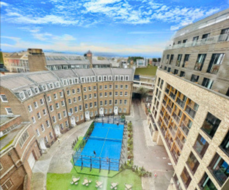 Aerial view of the padel court in the City of London's Crescent, EC3, surrounded by residential buildings with a blue swimming pool visible nearby